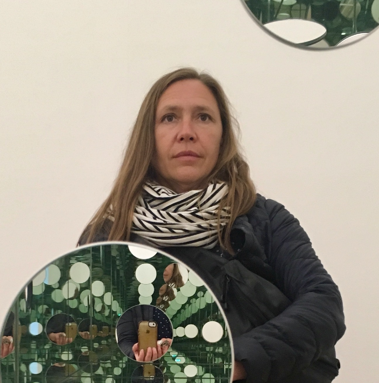 A woman facing forward, taking a selfie in an art installation.