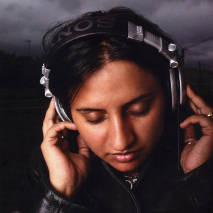 A woman wearing headphones, looking down.