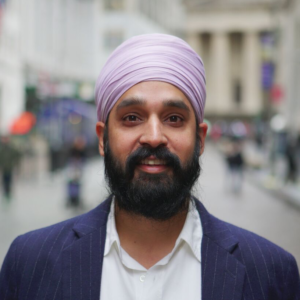 A bearded man in a suit wearing a lavender turban.