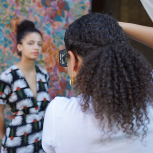 A woman taking a photo of another woman against a colorful backdrop.
